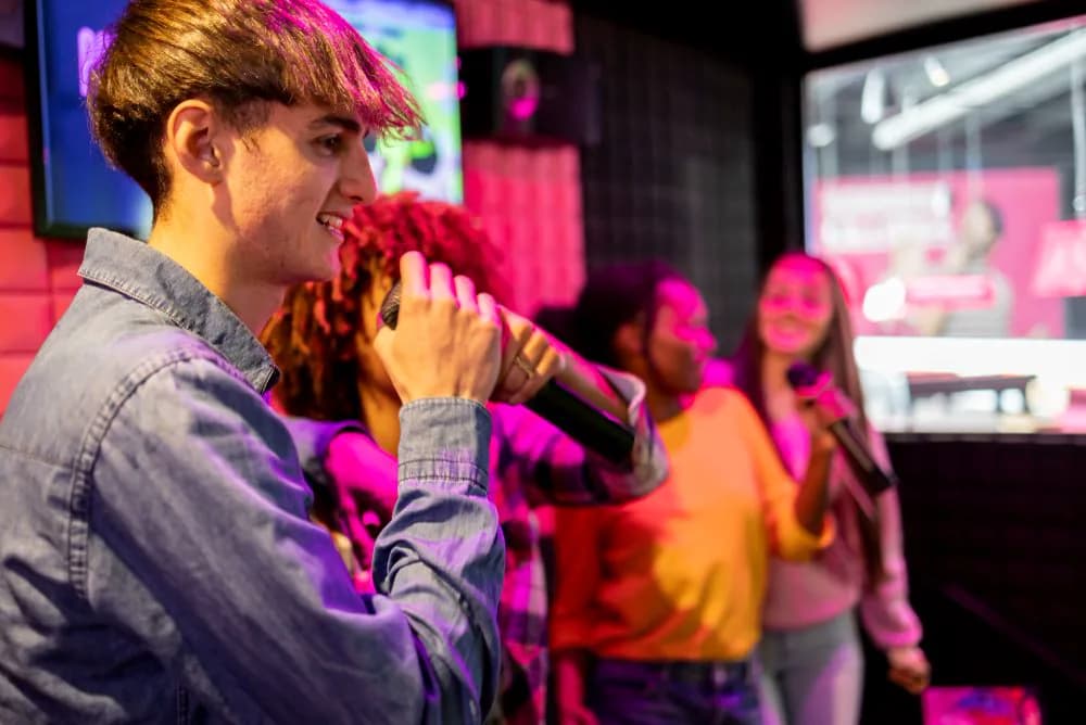 Un chanteur micro en main dans la karaoké box, sous les lumières roses
